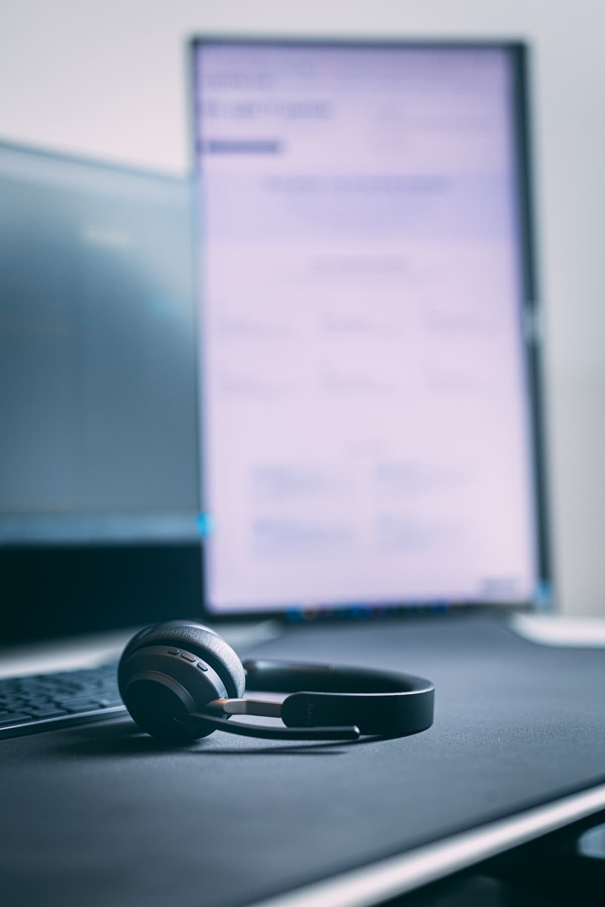 Monitor, med skærmbillede af drift overvågning. Der ligger et kundeservice-headset på skrivebordet. Virksomheden tilbyder it-drift og -support