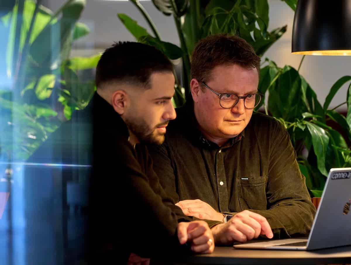 To medarbejdere fra Connexa sidder i et hyggeligt mødelokale og arbejder sammen på en laptop